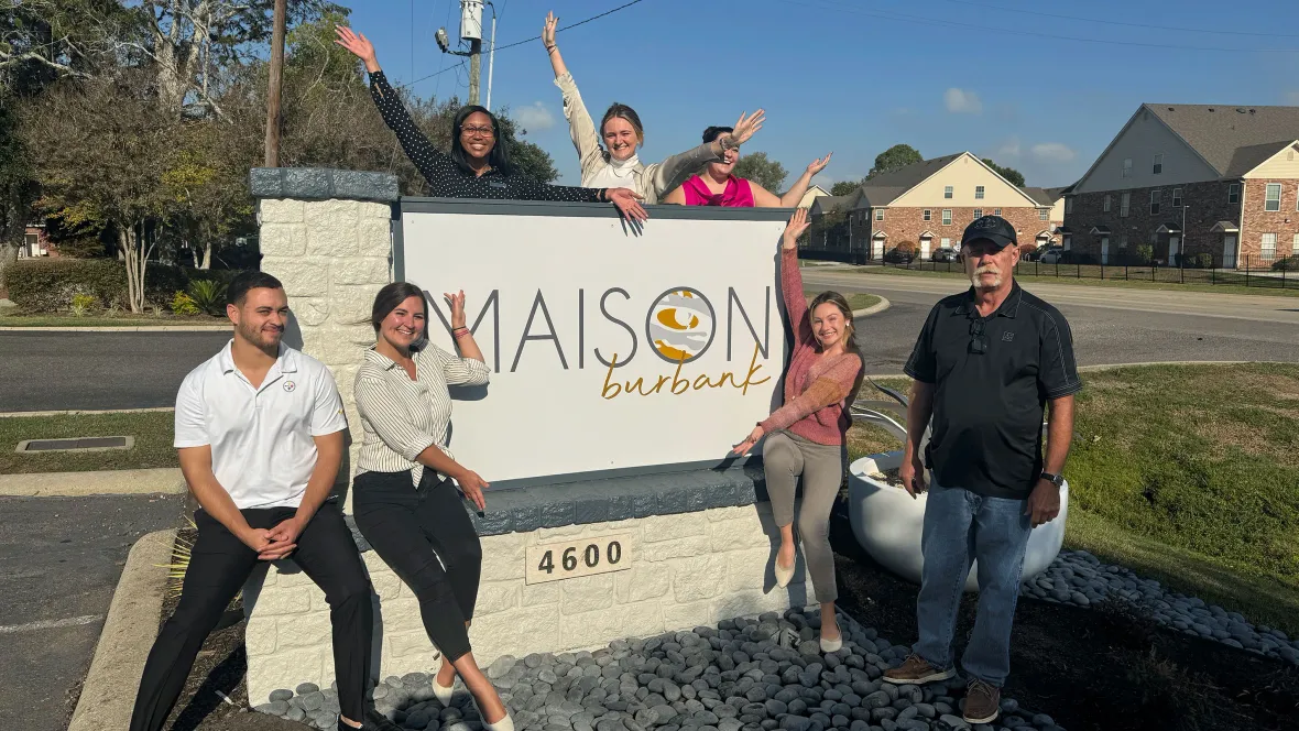 The Maison Burbank team in front of their sign that reads "Maison Burbank".