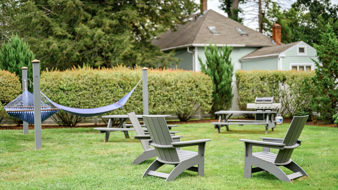 Our event lawn featuring Adirondack seating, two blue hammocks, a picnic table, and a gas grill.