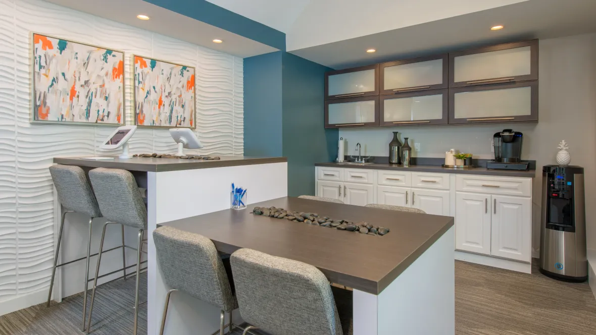 A modern, inviting leasing office with colorful décor, a single-serve coffee, a water refill station and desk space.