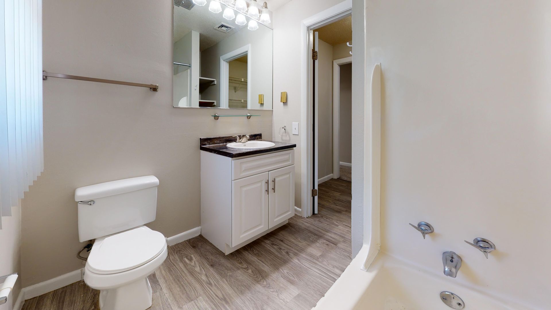 Bathroom in The Pioneer floor plan at Alpine Commons with a white vanity, large mirror, and combination bathtub and shower.
