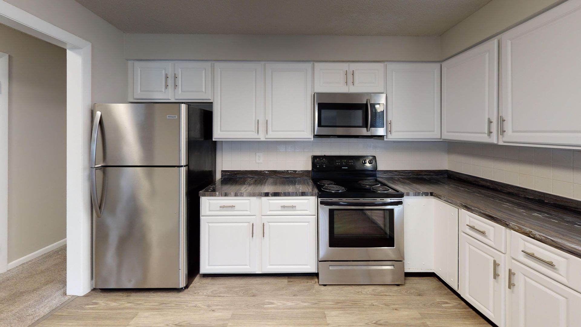 Stainless steel kitchen appliances and white cabinets in The Pioneer 3-bedroom apartment at Alpine Commons.