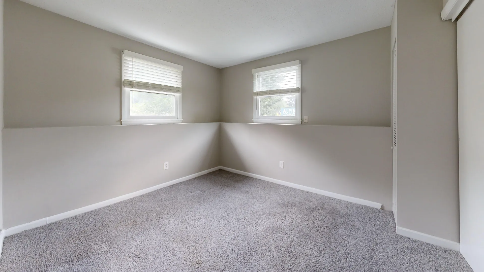 Bright bedroom in The Valley floor plan at Alpine Commons Apartments, showcasing large windows and a neutral color scheme.