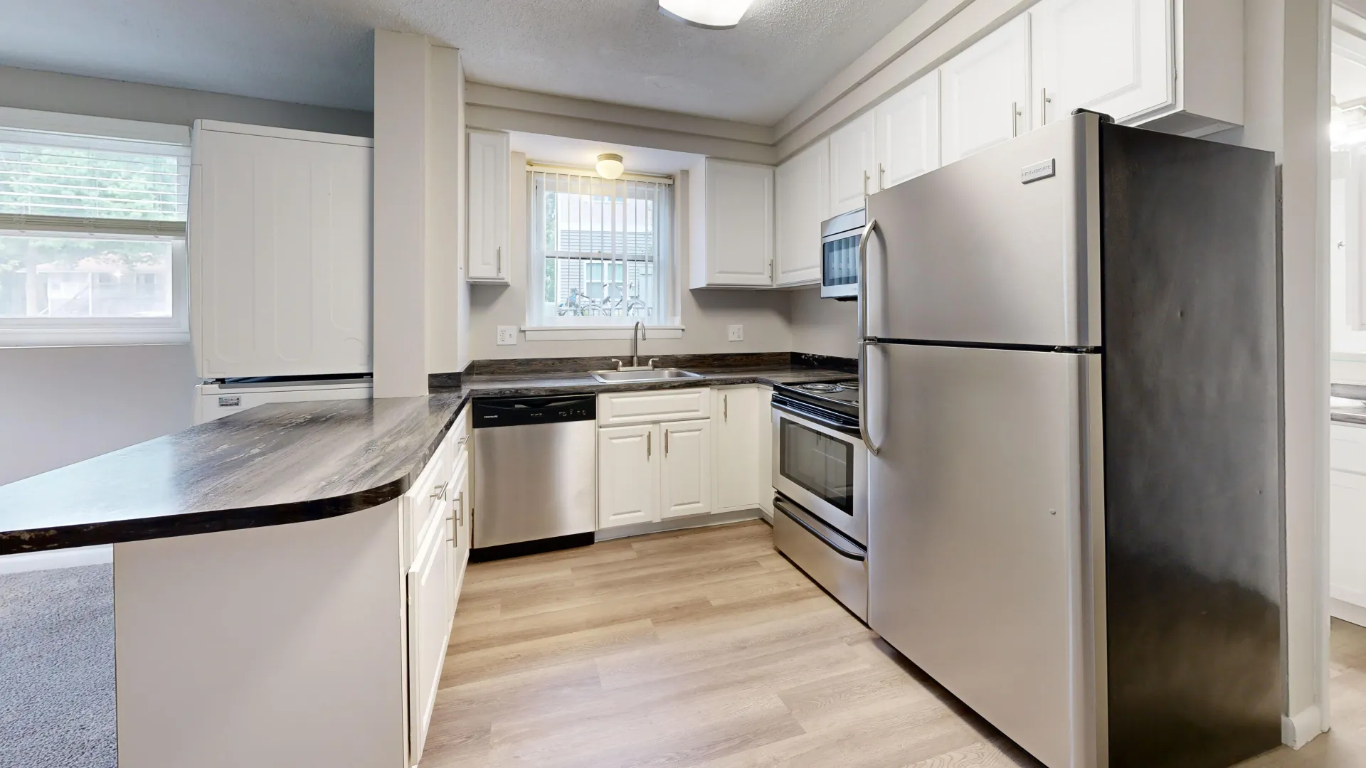 Modern kitchen in The Valley floor plan at Alpine Commons Apartments with stainless steel appliances, white cabinets, and elegant countertops.