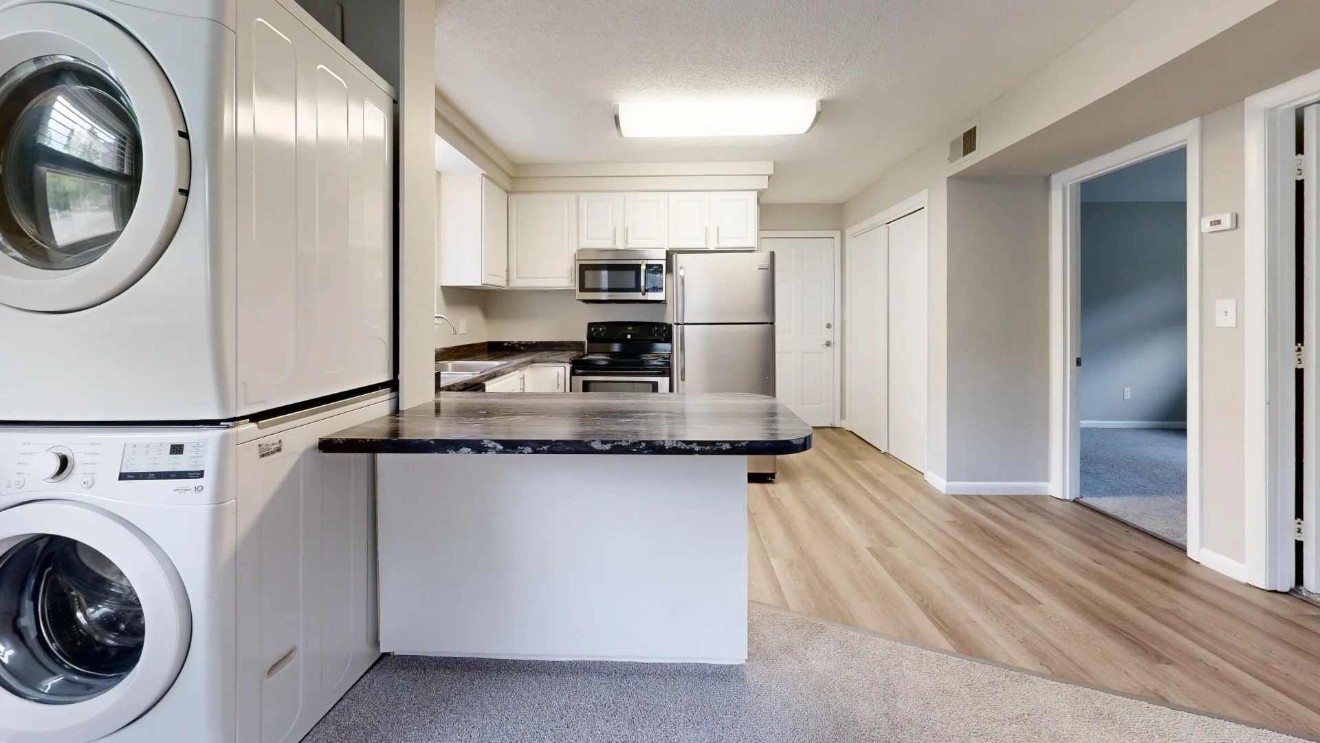 Kitchen area in The Valley floor plan featuring a washer and dryer, stainless steel appliances, modern countertops, and white cabinetry.