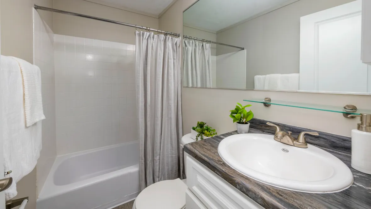 Spacious bathroom with modern design featuring a sleek expansive mirror.