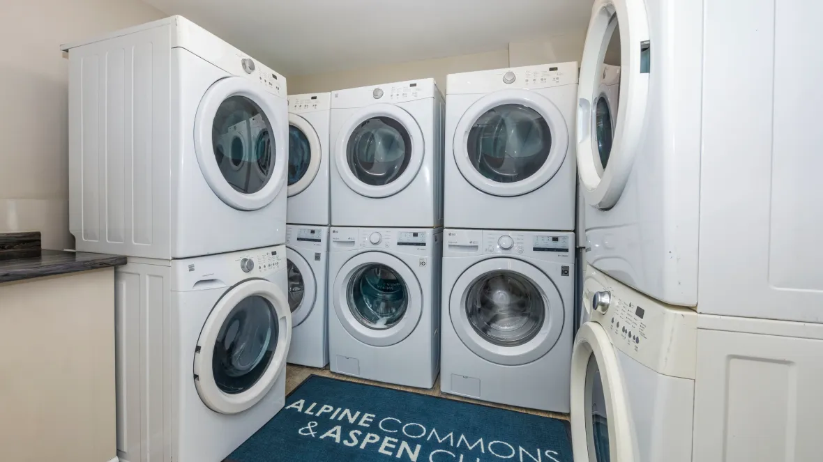 A community laundry room with five sets of washers and dryers and countertop space to conveniently fold laundry. 