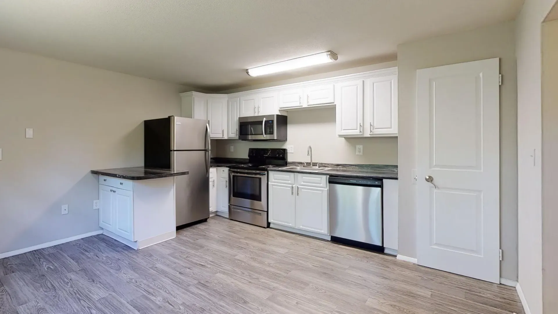 Modern kitchen in The Alma Mater with stainless steel appliances and white cabinets.