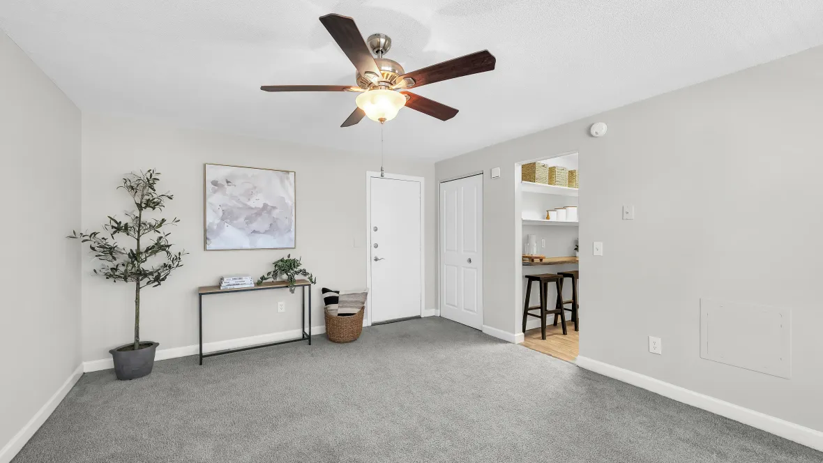 Living room of the studio apartment complete with carpeting throughout and a multi-speed ceiling fan. 