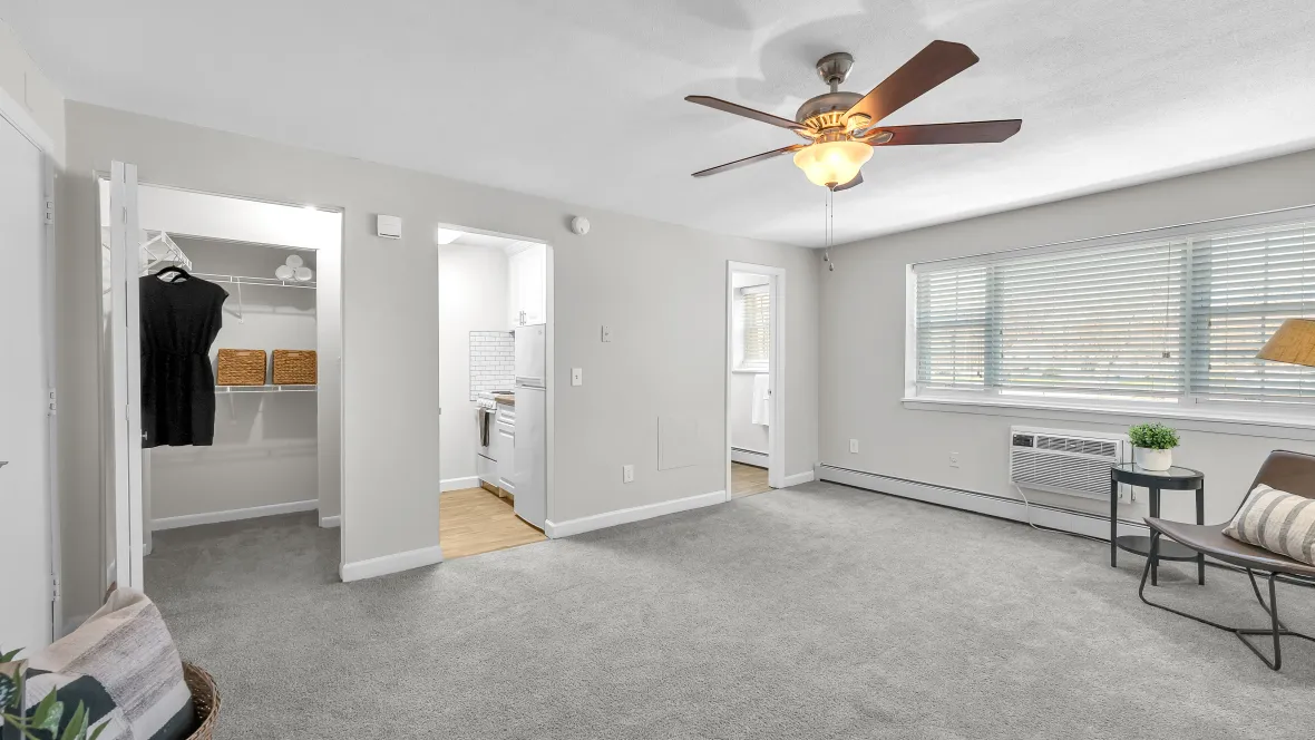 Studio apartment living area with large windows, baseboard heating, and an individual AC unit.