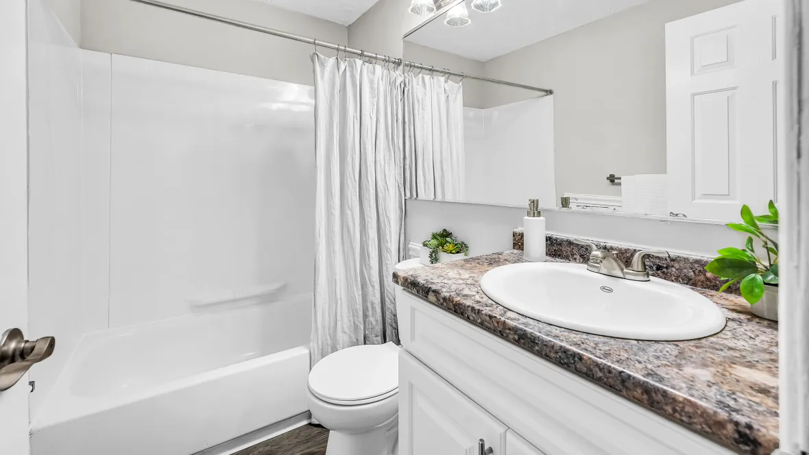 A bathroom with extended mirror and vanity lighting, upgraded countertops and cabinets, and garden bathtub.