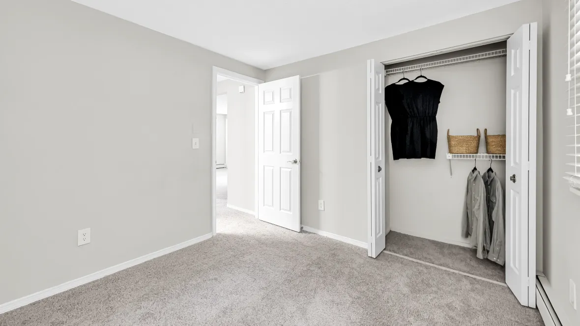 A view of the closet from the bedroom, which includes built-in staggered shelving for multiple levels of hanging and storing.