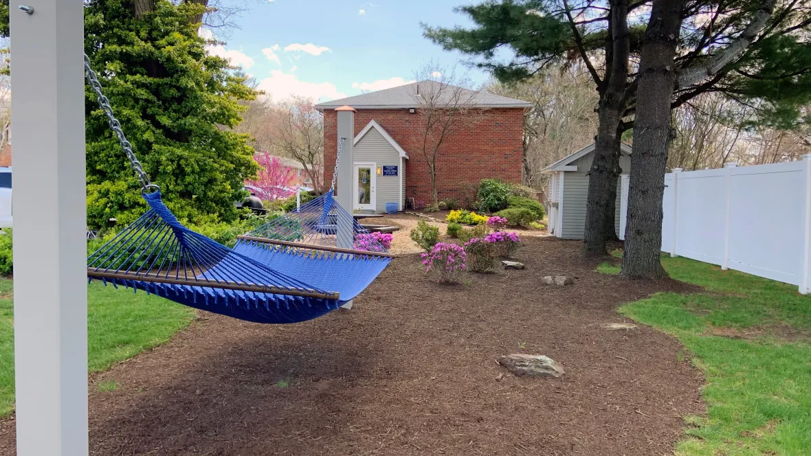 A blue hammock hanging over an outdoor garden space.