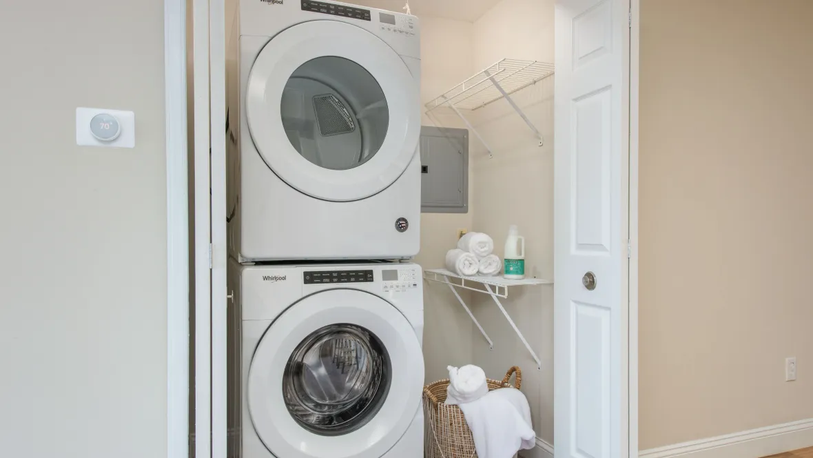 A stackable washer and dryer set inside of a closet within an apartment.