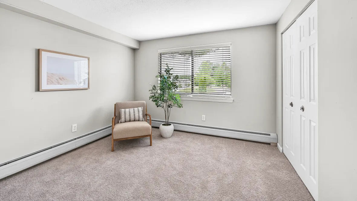 A spacious bedroom with plush carpeting, ample natural light from a large window, and a generous closet equipped with built-in organizers for ultimate serenity.