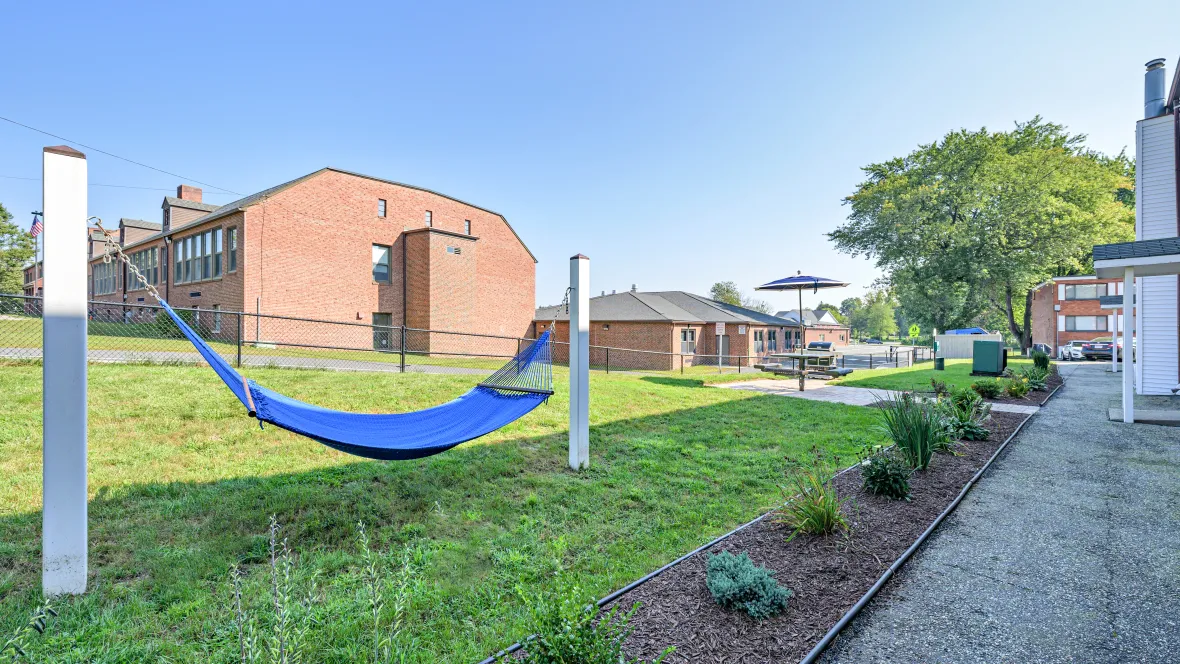 A hammock gently rocking in a serene, grassy area, next to a meticulously landscaped Zen garden.