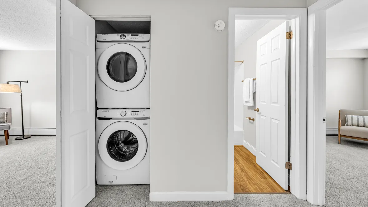 A convenient in-unit laundry setup with full-size washer and dryer units discreetly stacked in hallway closet for your ease and accessibility.