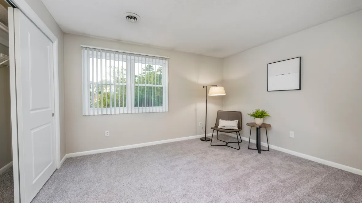 An expansive bedroom with plush carpeting, abundant natural light from a large window, and a generous closet equipped with built-in organizers, creating an elegant space for tranquil living.