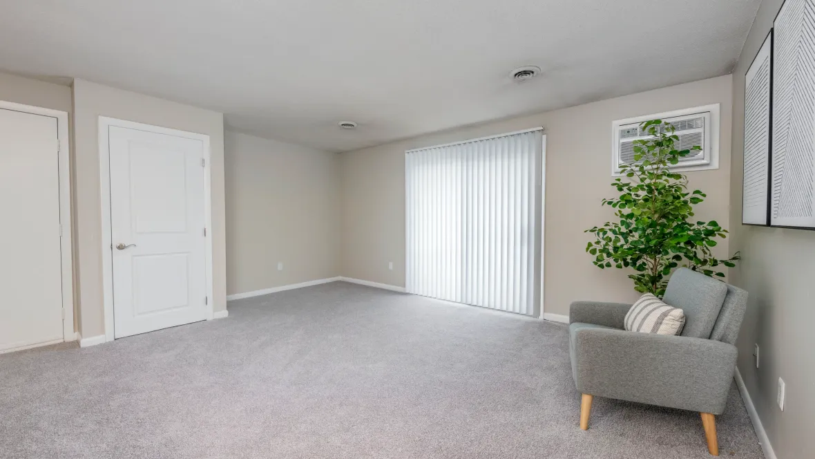 Spacious, carpeted living room with sliding doors with privacy blinds to a private balcony.