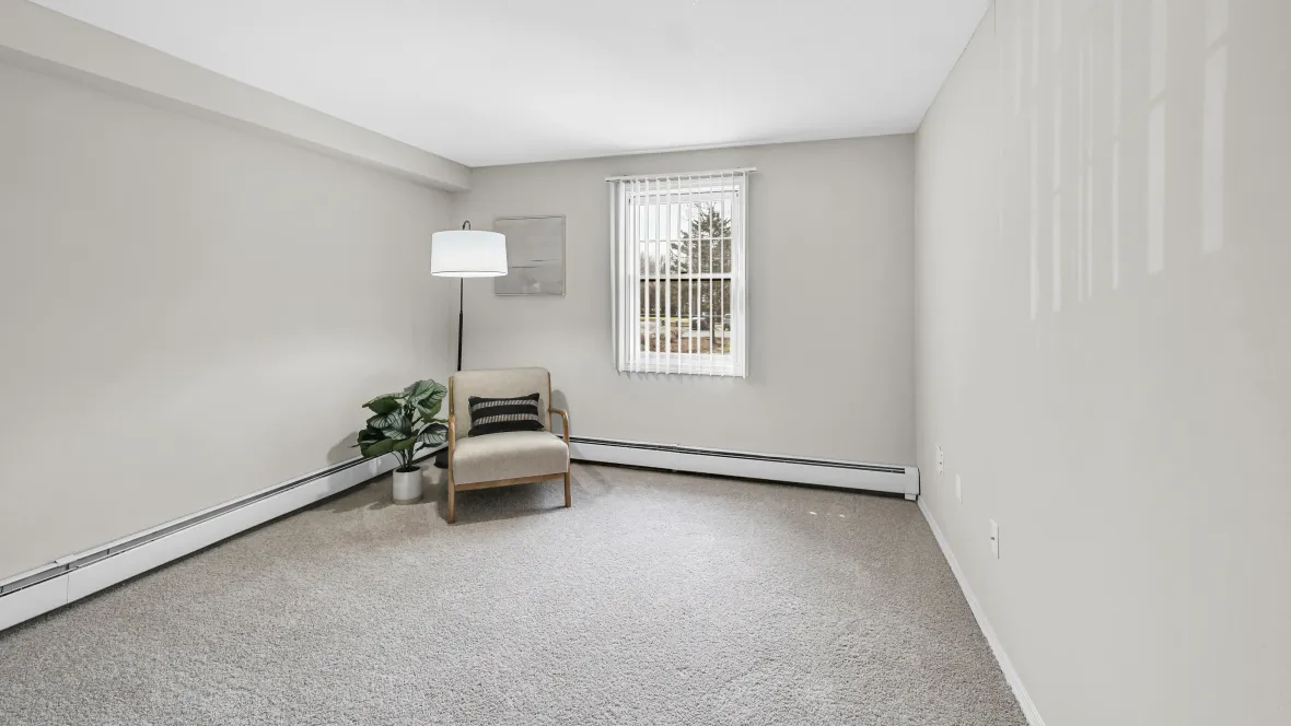 Bedroom with large window complete with privacy blinds and baseboard heaters. 