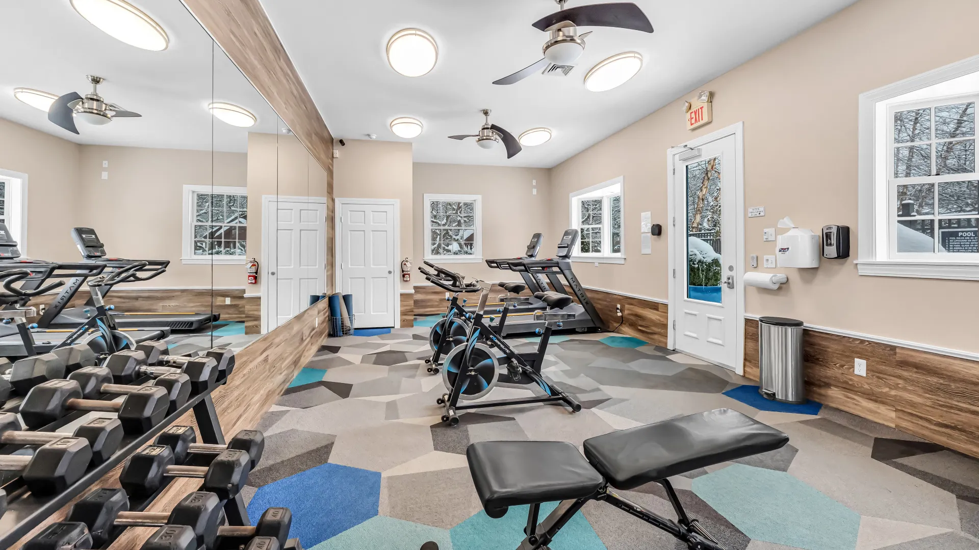 Fitness center featuring hand weights, workout bench, stationary bicycles and treadmills