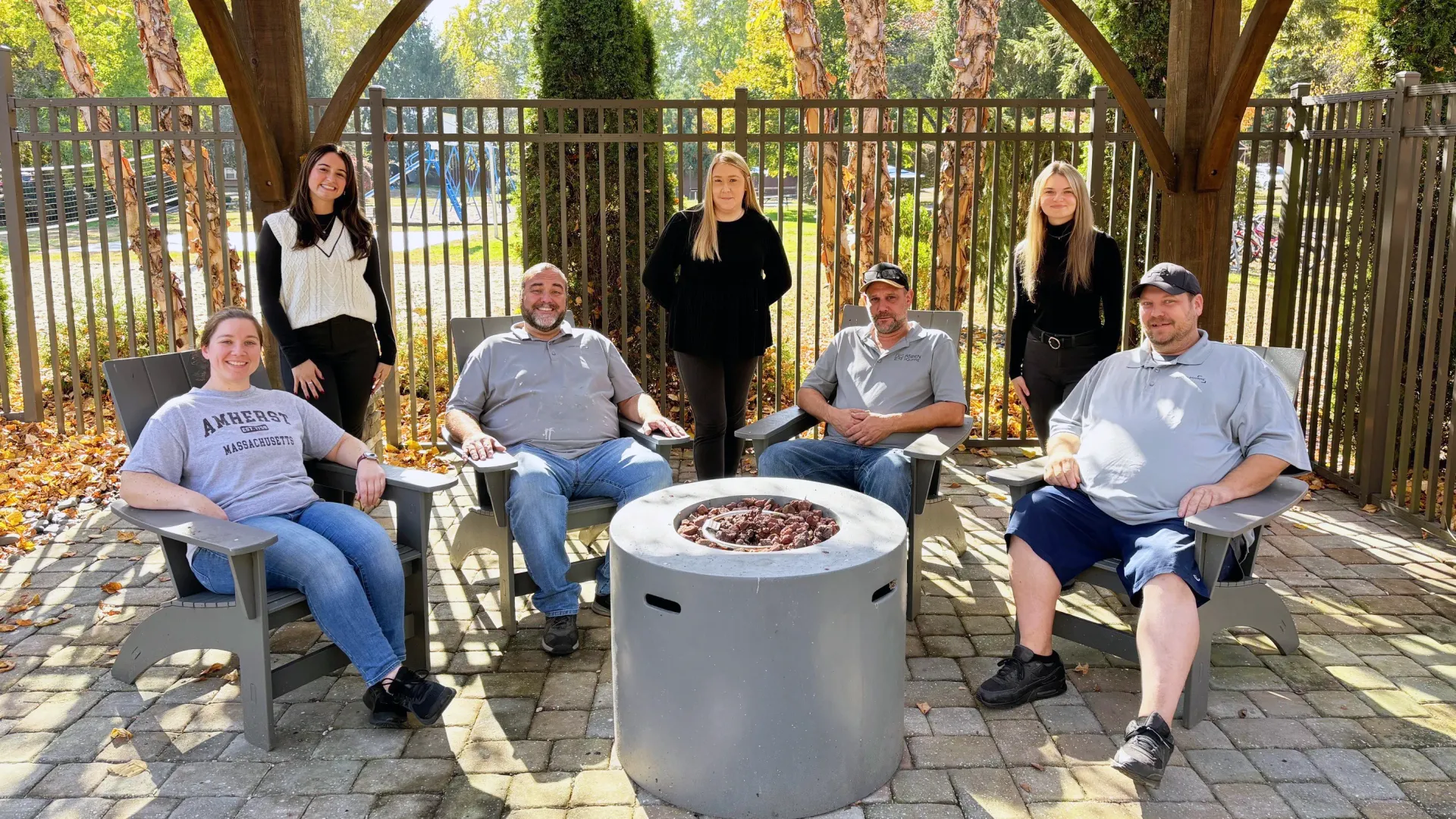 The team at Sugarloaf Estates gathered around a fire pit in the outdoor lounge, showcasing their dedication to maintaining a welcoming and well-kept community.