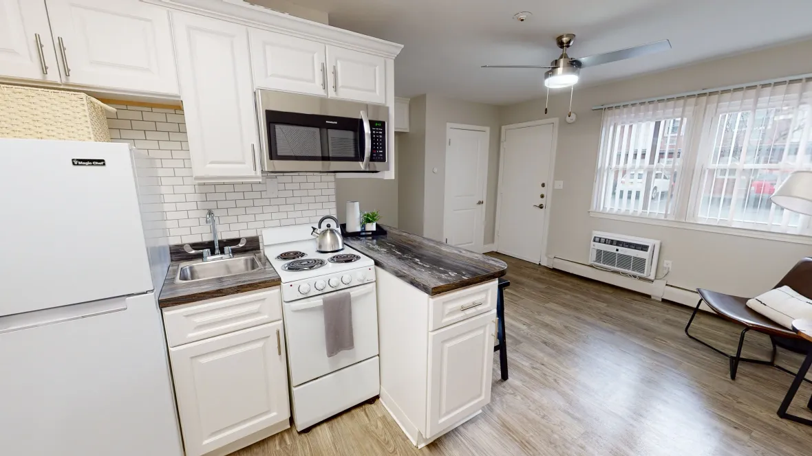 A charming kitchen featuring a sink, stove, microwave, refrigerator, and a convenient breakfast bar for seating.