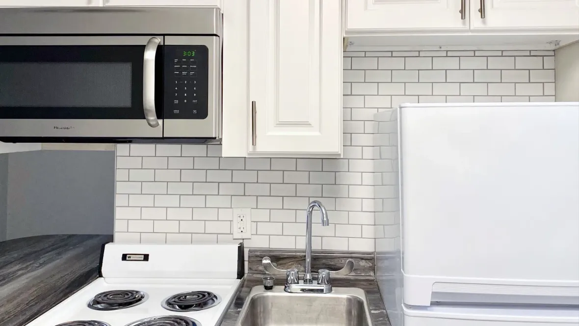 A close-up view of the white subway tile backsplash behind the kitchen sink, stove, and refrigerator, adding a touch of modern elegance.