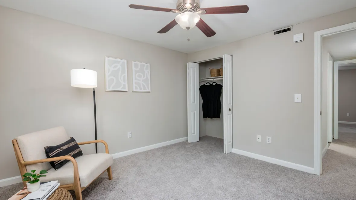Comfortable bedroom space with plush carpeting, a ceiling fan, and a spacious closet with double bifold doors.