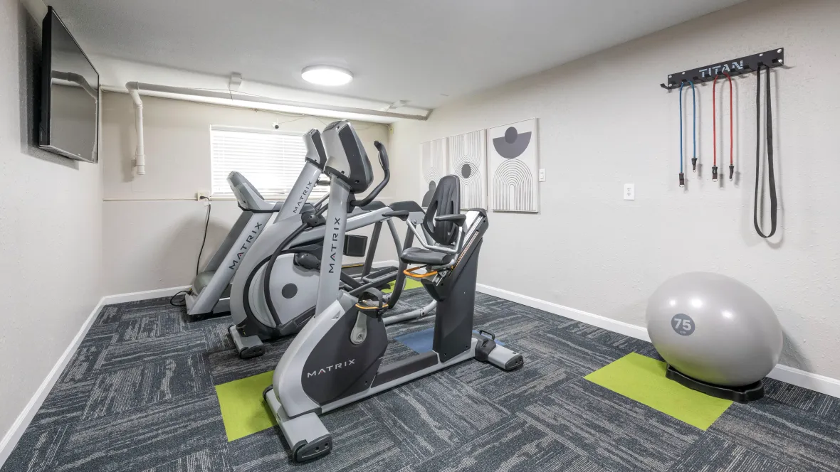 A well-lit fitness center with various cardio and stretch equipment, providing residents with 24/7 workout possibilities.