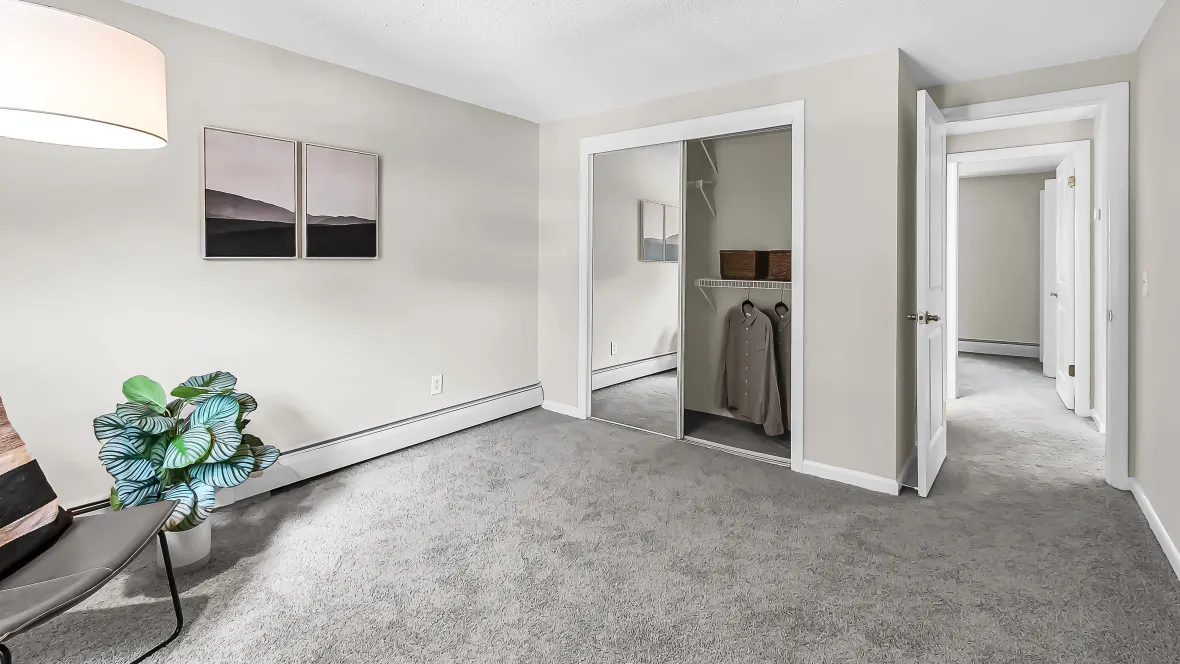 Bedroom closet with sliding mirrored doors, built-in open-wire shelving, and abundant space for effortless organization.