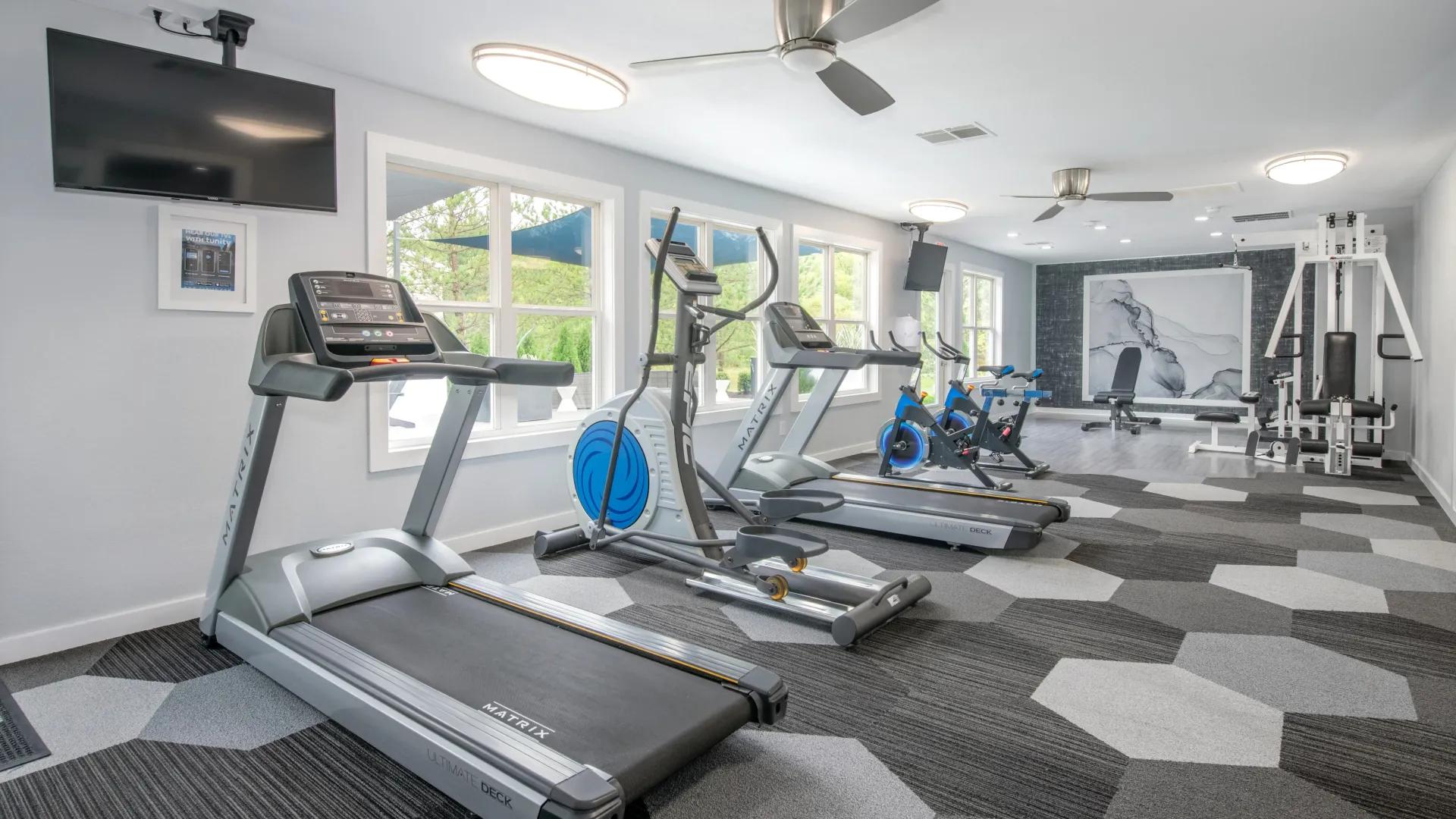 Modern fitness center with cardio and weight equipment with ceiling fans to help you feel cool while you work up a sweat.