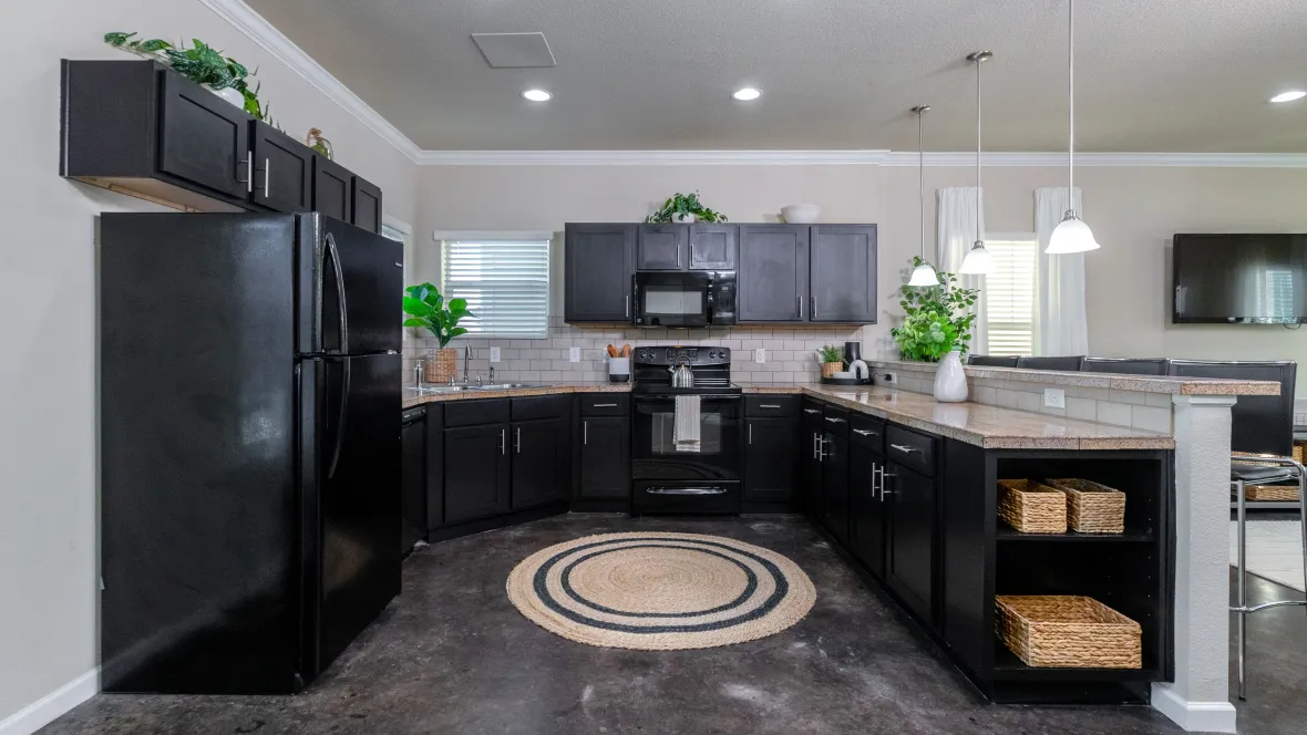 A large, open kitchen with sleek black cabinetry, marble countertops, breakfast bar, and full kitchen appliance package.