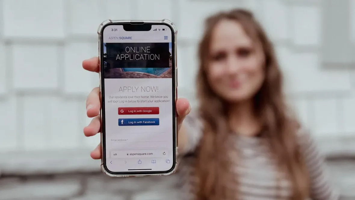 A girl holding up a cell phone to the camera that shows our online application.