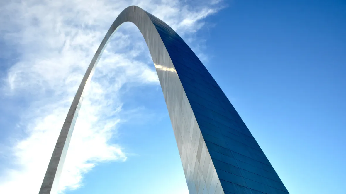 A photo of the Gateway Arch located in St. Louis, MO over a beautiful blue sky background.
