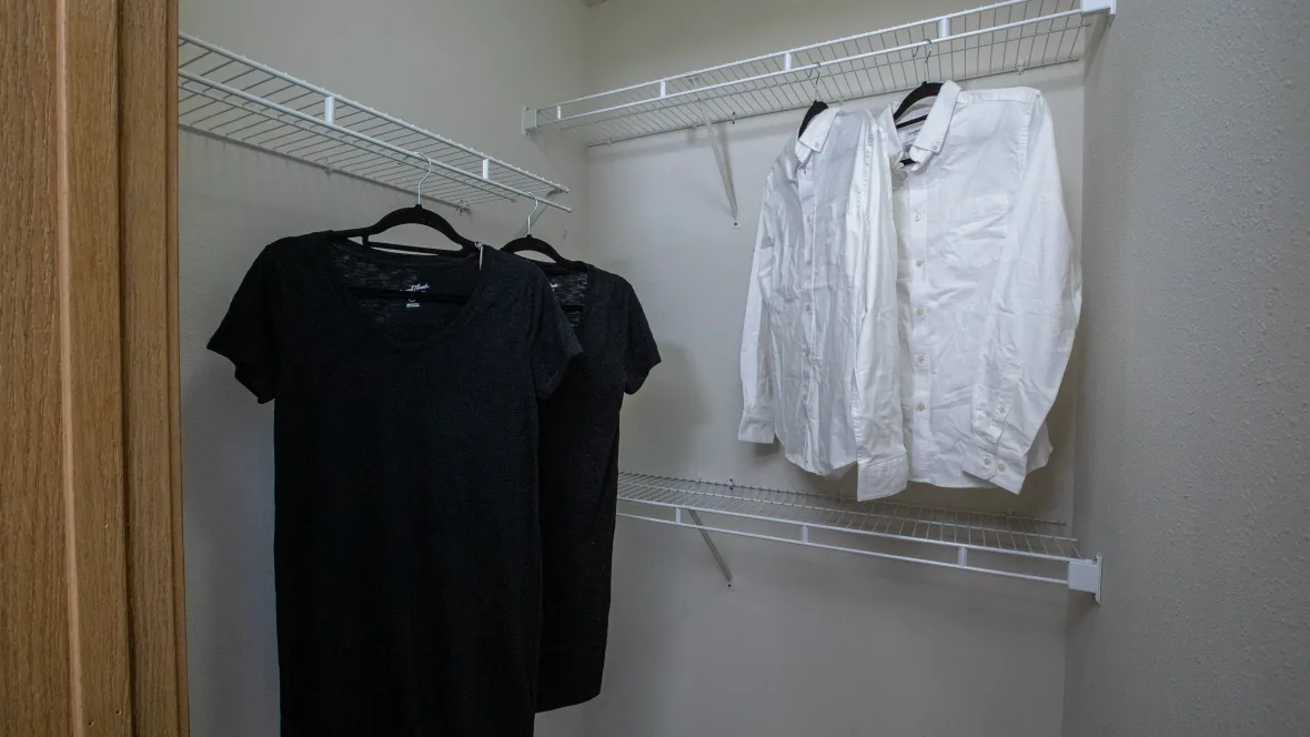 A generously sized walk-in closet with expertly organized clothing and staggered shelving.