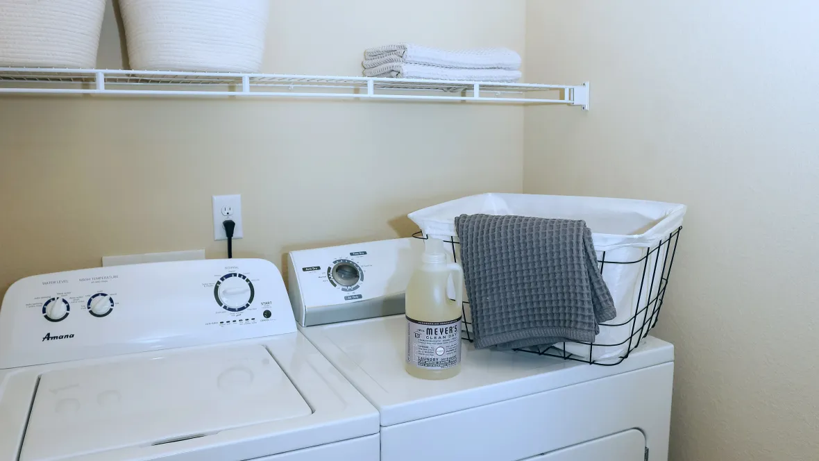 A laundry room featuring a full-size, side-by-side washer and dryer combination with a handy shelf above.