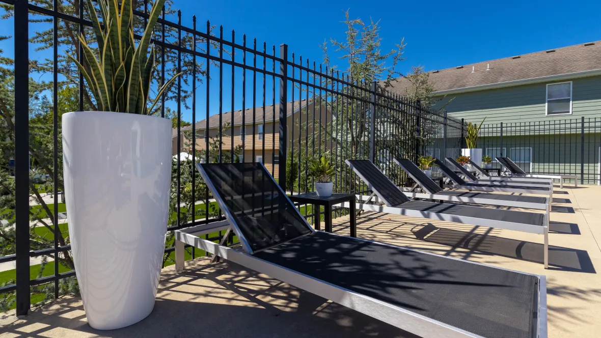 Chic black and silver sun loungers with convenient side tables lined up along the pool boundaries.