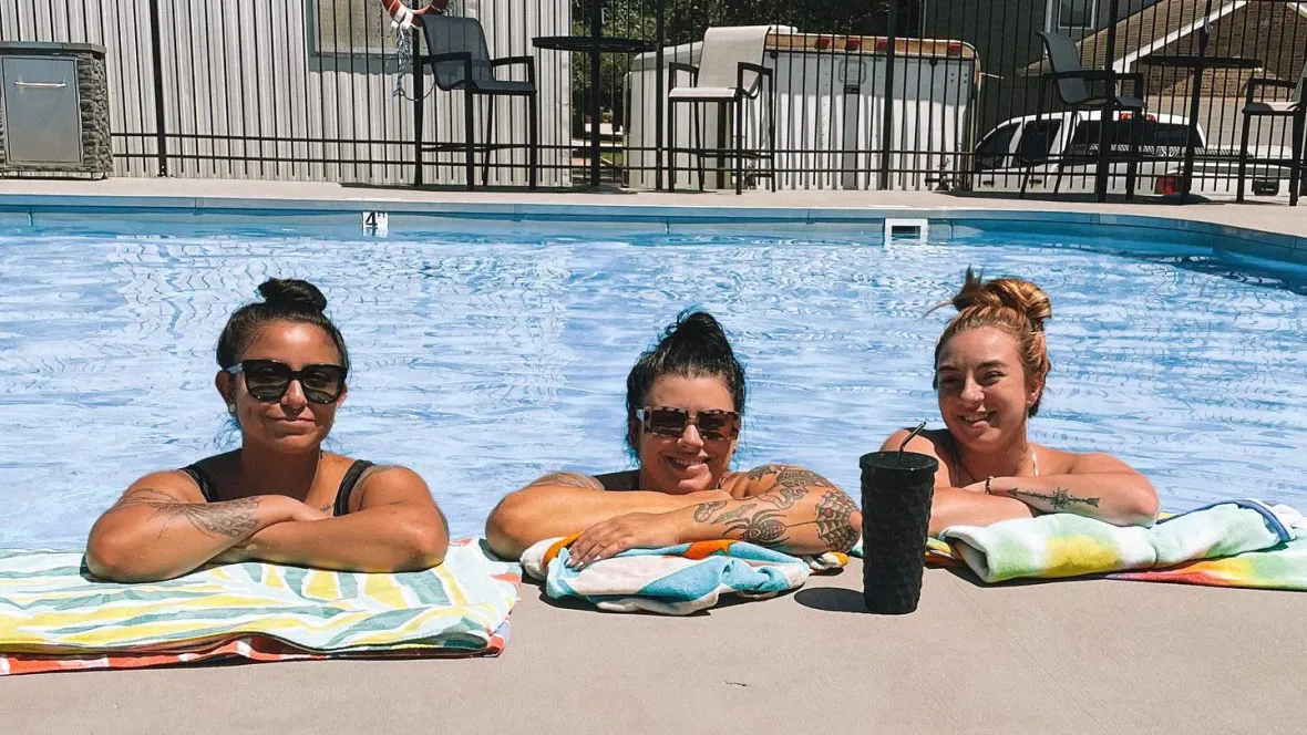 Three residents posing for a photo in our pool with their arms crossed on the side of the pool.