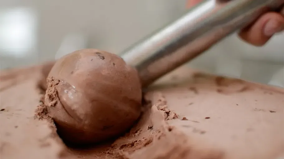 An ice cream scoop, scooping chocolate ice cream