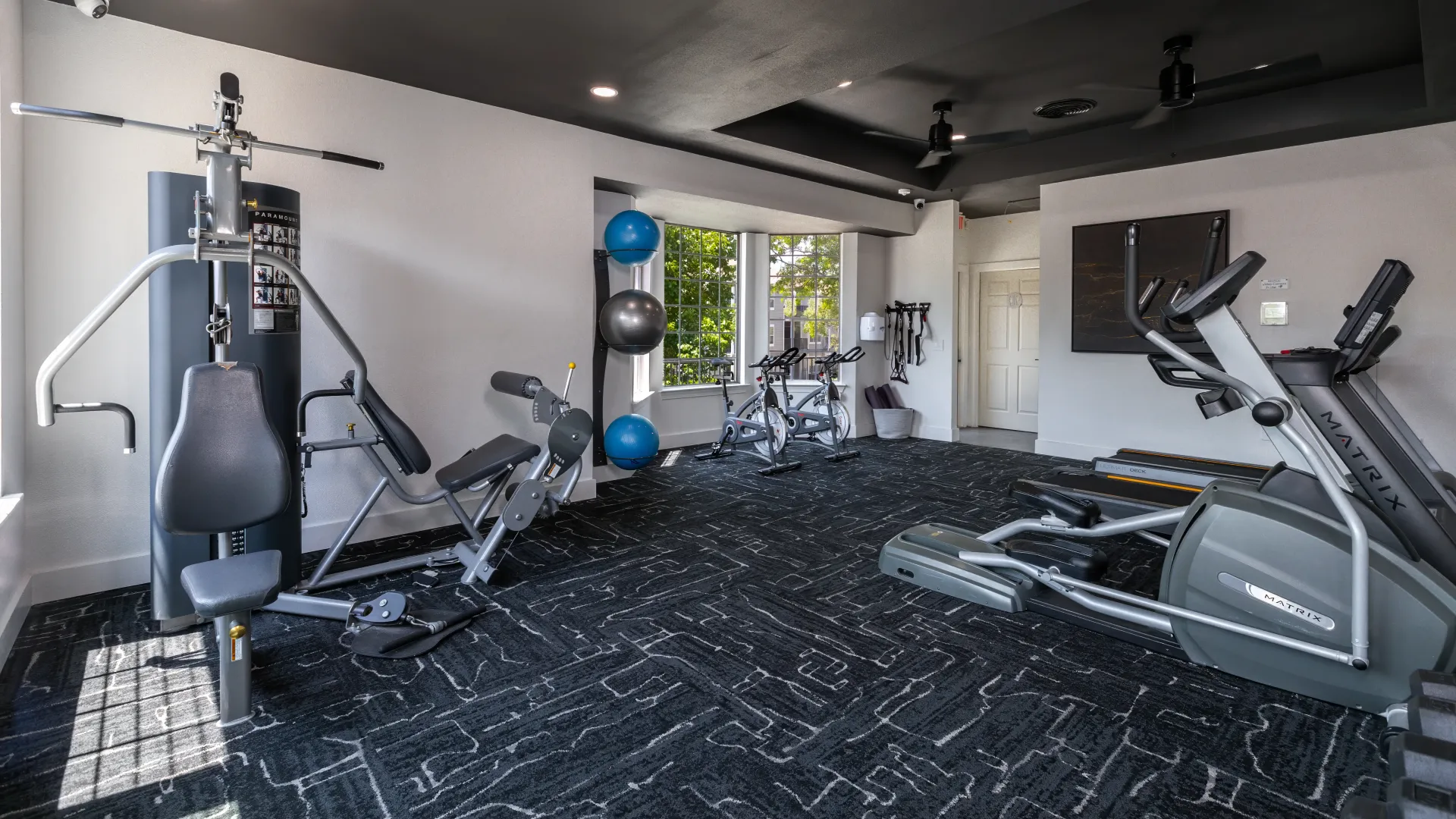 Modern fitness center with treadmills, ellipticals, weight machines, exercise bikes, and exercise balls.