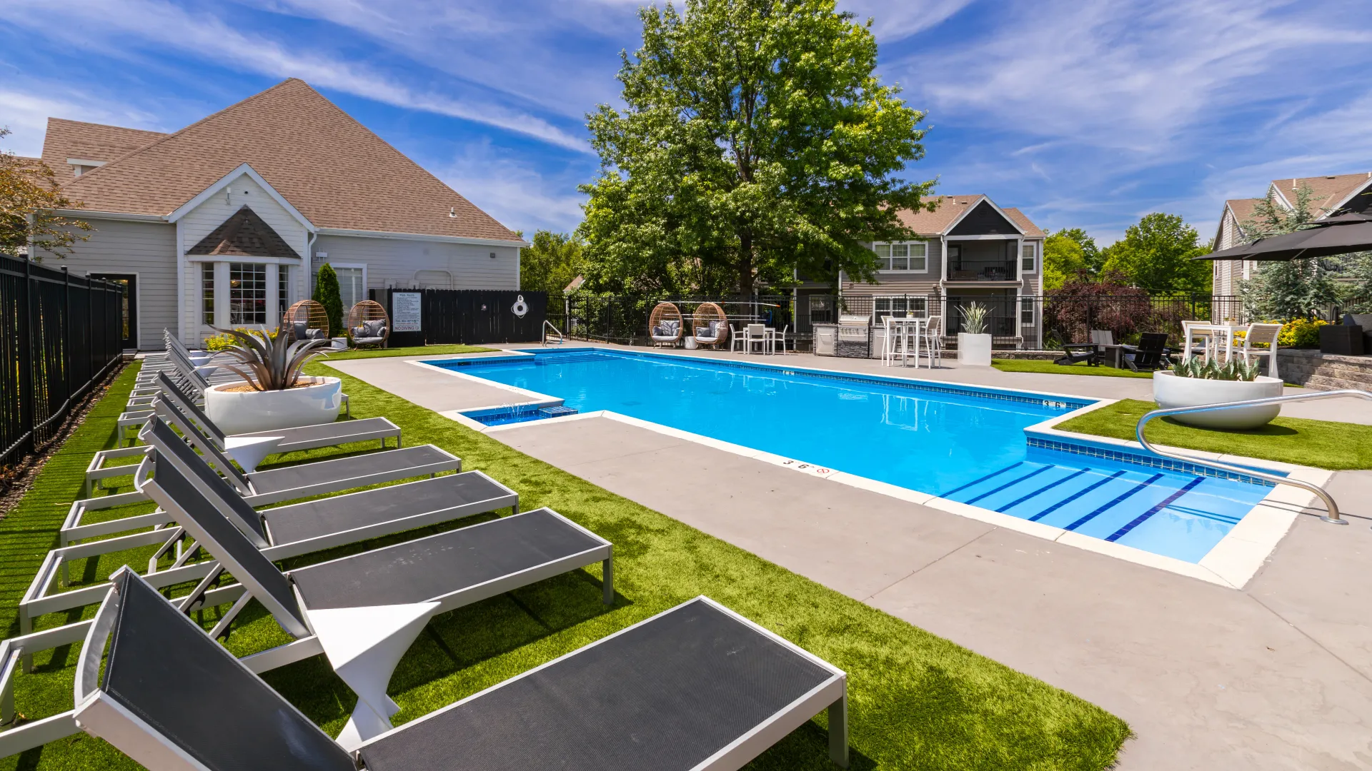 Outdoor swimming pool with lounge chairs, seating areas, and landscaped surroundings.