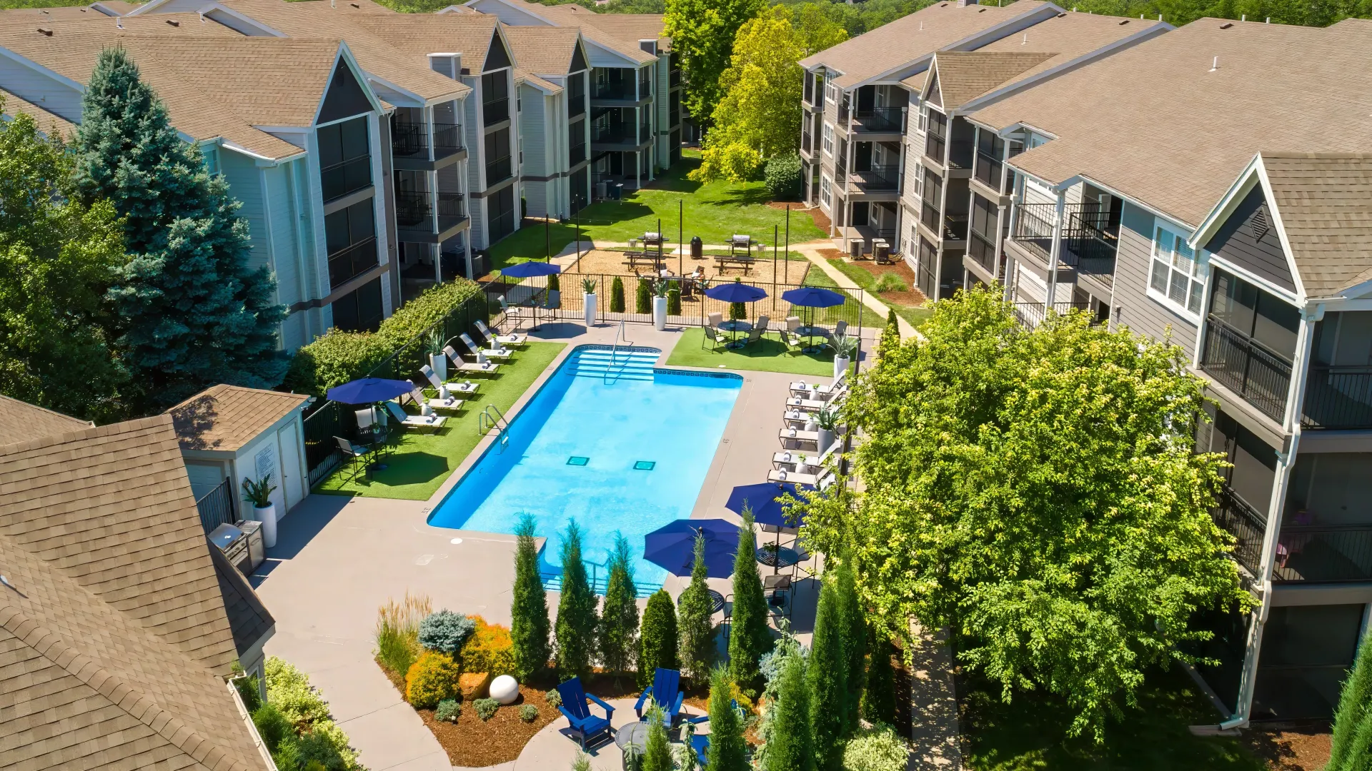 An overhead view of the vibrant pool and spacious pool deck tucked between apartment buildings. 