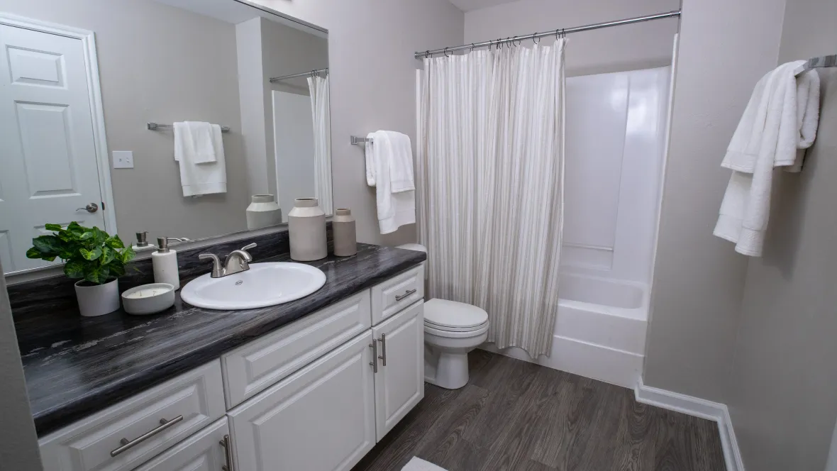 A bathroom with upgraded countertops and cabinetry, garden-style tub, and vanity lighting.