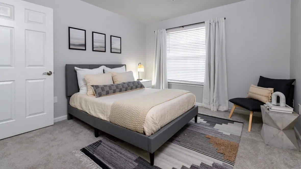 A master suite made cheerful by a wide window and lavish carpeting.