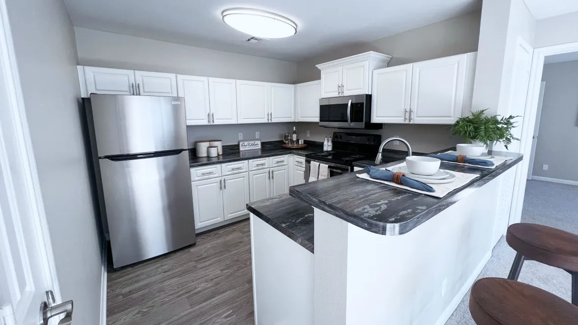 A spacious kitchen with ample white cabinetry, expansive breakfast bar, and full stainless steel appliance package.