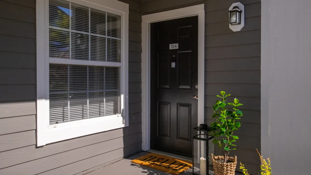 An inviting private entry porch with a welcome mat leading to the front door of the apartment home.