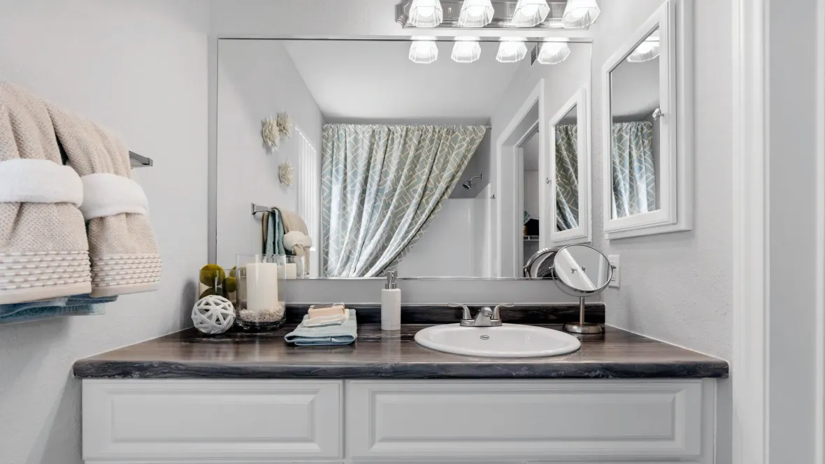 A well-lit vanity space boasting expansive countertops, a large mirror, and ample cabinet storage below.