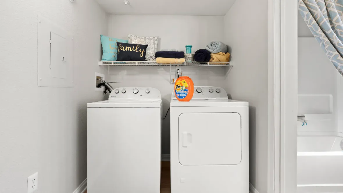 A full-size washer/dryer set with a storage shelf above, in a large laundry space just off from the master bathroom for a convenient location.