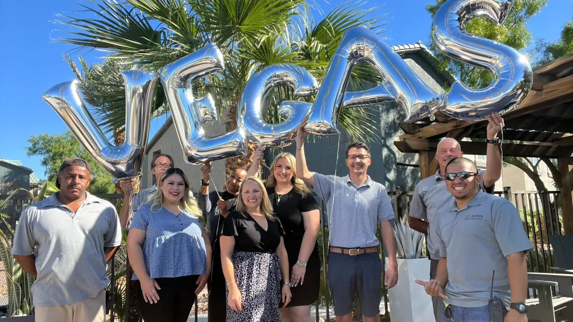 A group photo of the Millennium East staff holding balloons that spell out "Vegas".