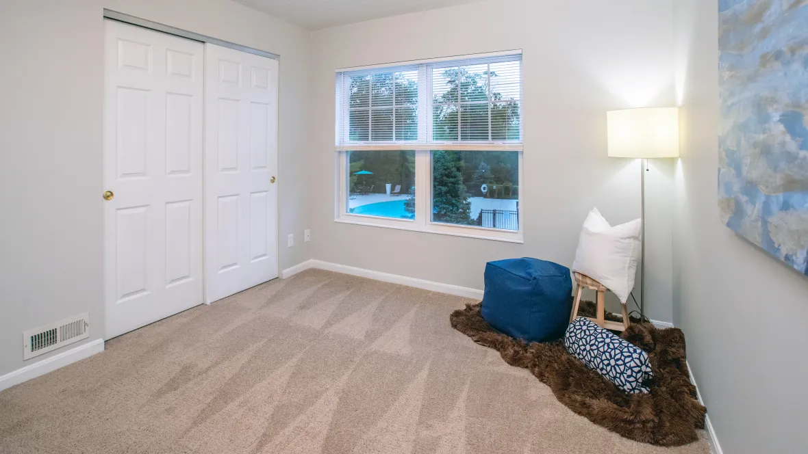 A comfortable bedroom with large windows and neutral carpeting for the ultimate warmth. 